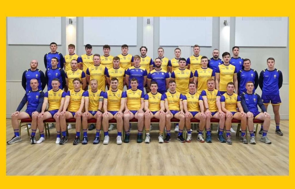 Team photo of a rugby squad in yellow and blue uniforms, posing in a group indoors.