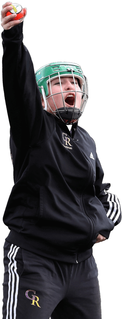 Person in sports gear celebrating with raised arm and ball, wearing green helmet with cage, outdoors.