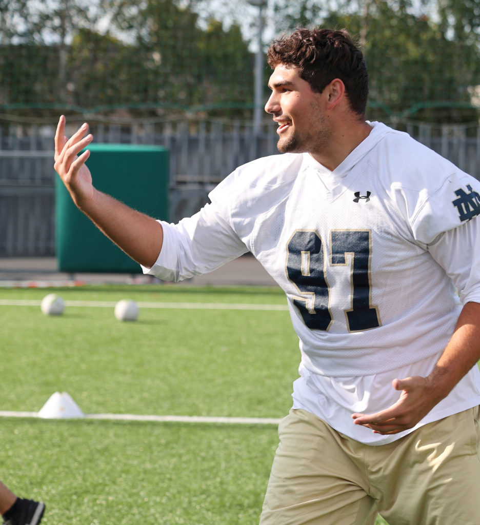 Football player wearing jersey number 97 practices on a sunny field, engaging with teammates.