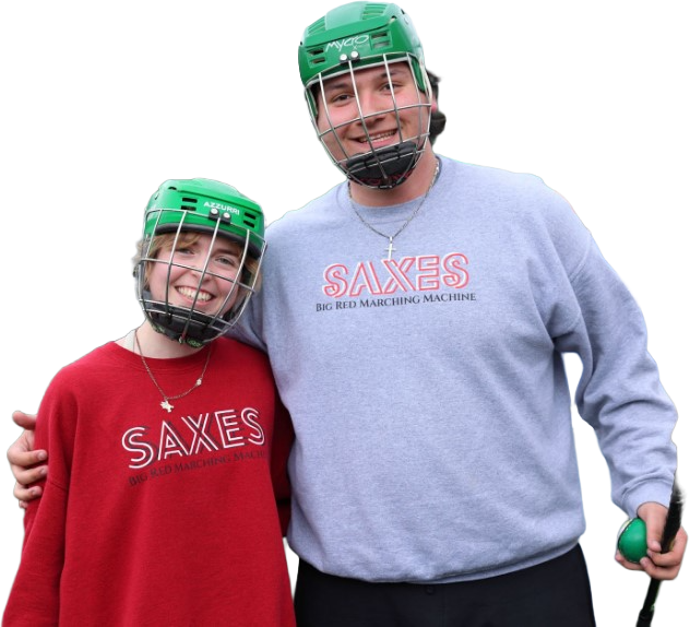 Two people in helmets smiling, wearing SAXES Big Red Marching Machine sweatshirts, posing happily together.