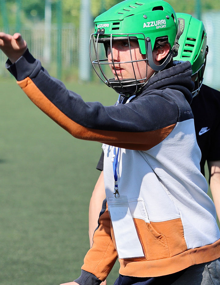 Person wearing a green sports helmet giving instructions on a field.