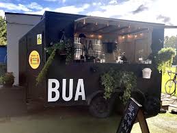 Mobile coffee shop BUA with plants and outdoor seating, perfect for enjoying a sunny day.