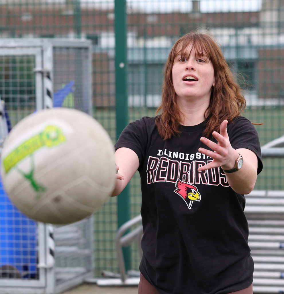 Woman playing volleyball outdoors in Illinois State Redbirds shirt.