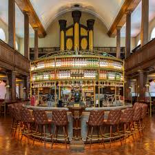Elegant bar interior with circular seating, ornate design, and high ceilings, creating a grand and inviting atmosphere.