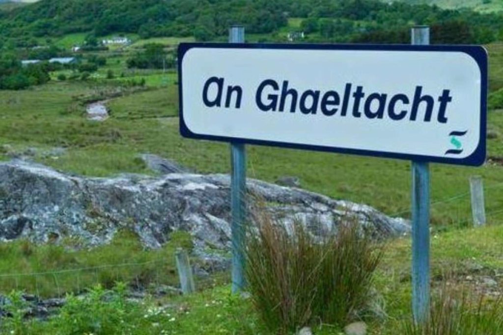 Sign for An Ghaeltacht in a lush green Irish countryside, showcasing Ireland's native language regions.