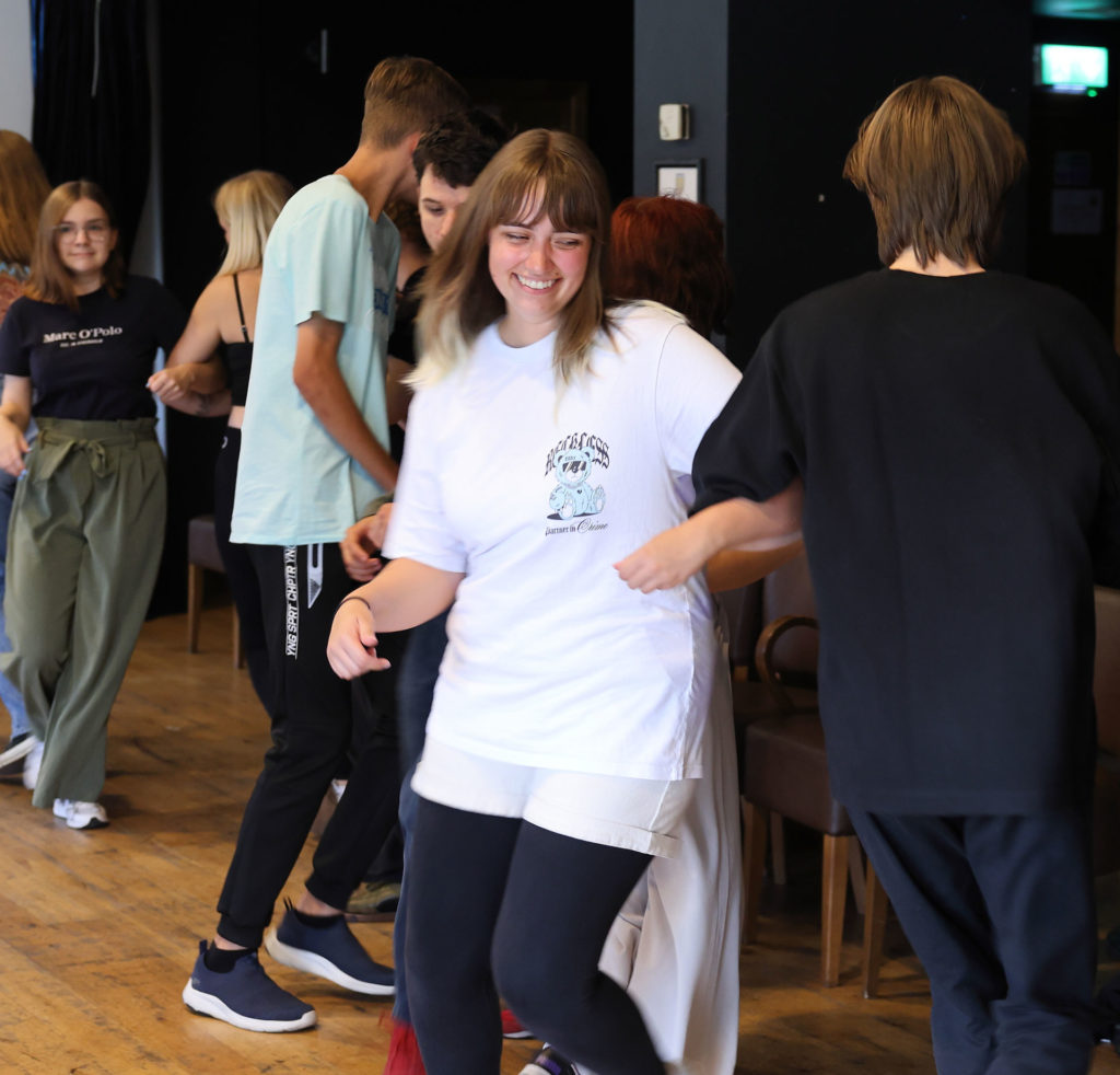 Group of young people dancing happily indoors, enjoying a lively social event.